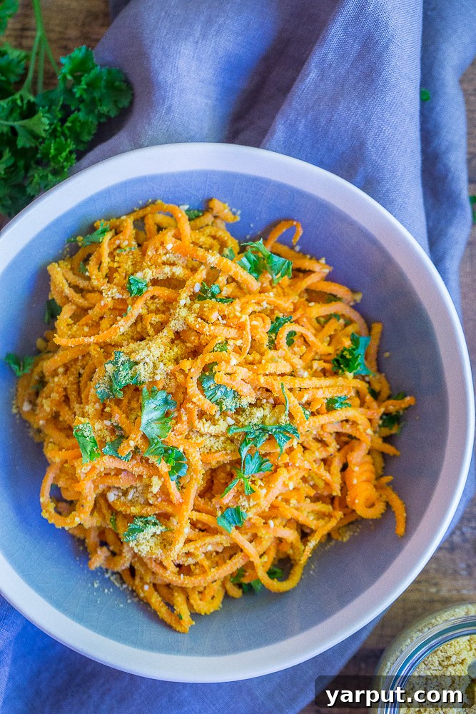 A rustic shot of Garlic Parmesan Sweet Potato Noodles in a pan, showcasing their texture and rich color, ready to be served.