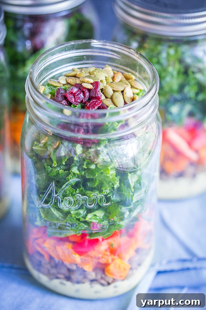 Sweet Potato, Lentil, Kale Prep Bowls with Curry Tahini 3 Close-up shot of a single Sweet Potato, Lentil, and Kale Meal Prep Salad layered in a mason jar, showcasing the colorful ingredients including tender sweet potatoes, hearty lentils, fresh kale, and a creamy Curry Tahini Dressing.