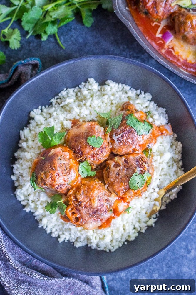 Hearty Sweet Potato and Black Bean Veggie Meatball Enchilada Bake 5 Vegetarian meatballs in a skillet before baking with enchilada sauce and cheese, ready for the oven.