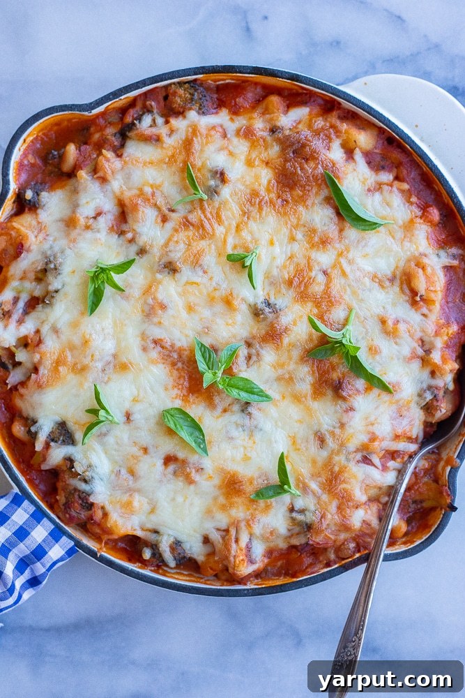 Effortless Five-Ingredient Gnocchi, Broccoli & White Bean Bake 5 A baking pan filled with the golden-brown gnocchi bake, adorned with melted cheese and fresh basil leaves, ready to be served.