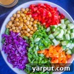 Close-up of Asian Chickpea Chopped Salad with dressing drizzled, showcasing fresh ingredients and a rich, creamy texture.