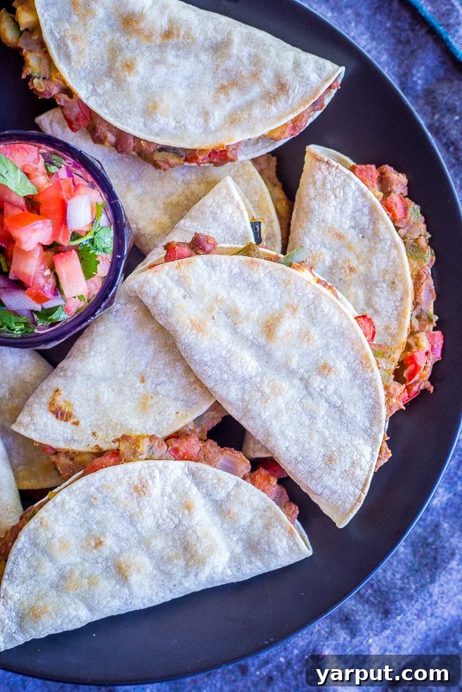 Baked Tacos Bursting with Summer Vegetables 3 A plate of perfectly crispy baked tacos filled with summer vegetables and refried beans, served with a side of homemade salsa for a refreshing meal.