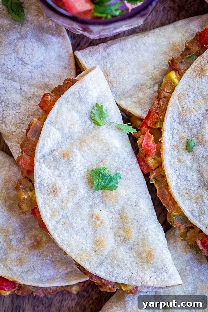 Baked Tacos Bursting with Summer Vegetables 6 Close-up view of two crispy baked tacos, highlighting their golden-brown, crunchy tortillas and the vibrant, textured filling of summer vegetables and refried beans.