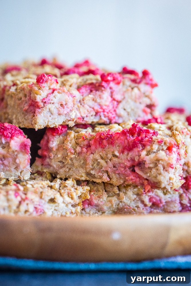 Sun-Kissed Lemon Raspberry Baked Oats 4 Lemon Raspberry Baked Oatmeal stacked up on a wooden plate