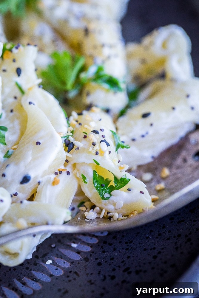 Close up of a single strand of 30 Minute Creamy Goat Cheese Pasta with Everything Bagel Spice on a fork.