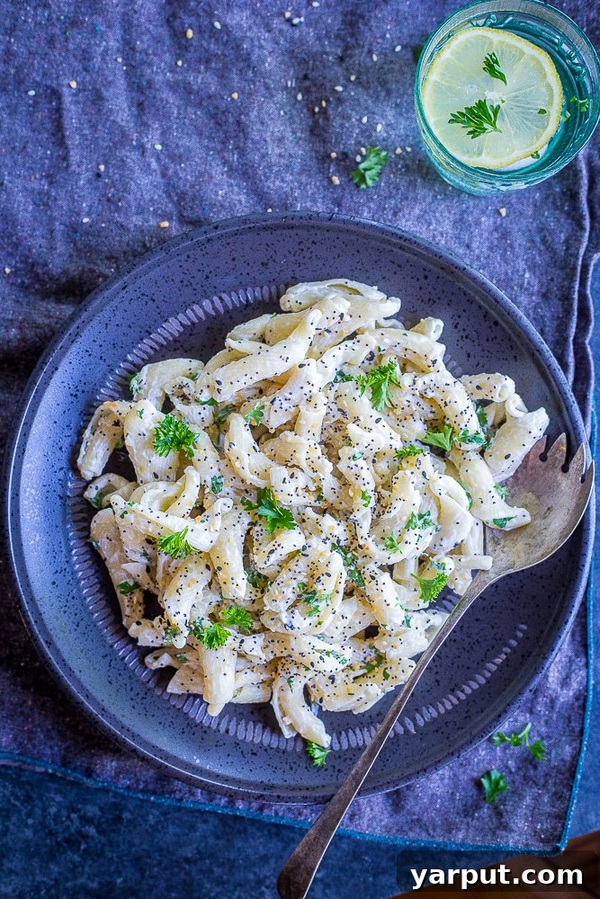 Overview of a plate of 30 Minute Creamy Goat Cheese Pasta with Everything Bagel Spice and a glass of water with a lemon in it, ready to be served.