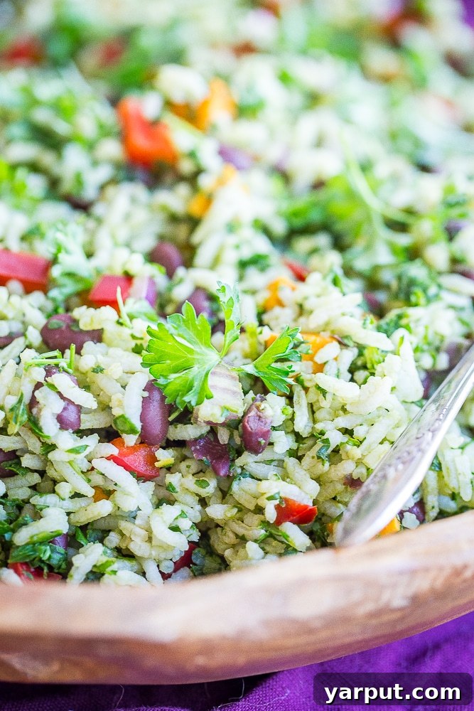 A close-up shot of the vibrant Green Rice with Black Beans and Sweet Potato in a rustic wooden bowl, highlighting the texture of the rice, beans, and sweet potato, and the verdant green color from the herbs.