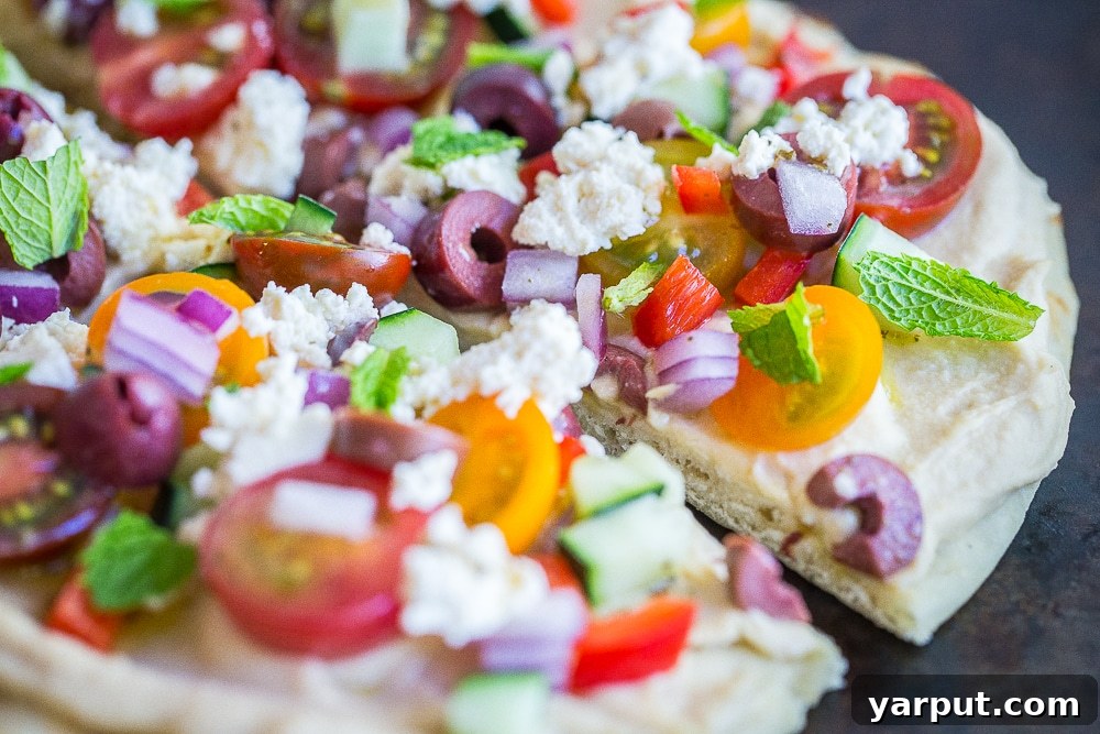 Side view of a No Cook Mediterranean Hummus Pizza, showing the layers of ingredients