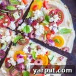 A No-Cook Mediterranean Hummus Pizza, vibrant with fresh toppings and ready to eat.