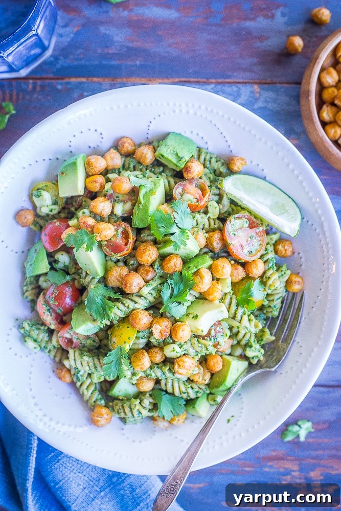 Tex-Mex Pesto Pasta with Crispy Chickpeas 2 A vibrant bowl of Southwestern Pesto Pasta with golden crispy chickpeas, accompanied by a refreshing glass of water and a separate small bowl of crispy chickpeas.