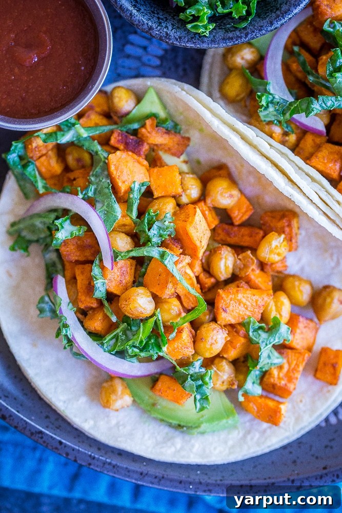 Sunshine Tacos: Sweet Potato, Chickpea, & Lemon Kale Slaw 3 A close-up view of a fully assembled Sweet Potato and Chickpea Taco, showing the roasted sweet potatoes, spiced chickpeas, and vibrant lemony kale slaw nestled in a corn tortilla, ready to be enjoyed.