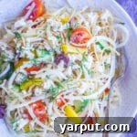 A vibrant close-up of the Healthy Greek Pasta Salad with Kohlrabi Noodles, featuring colorful vegetables and a fresh look, in a white bowl.