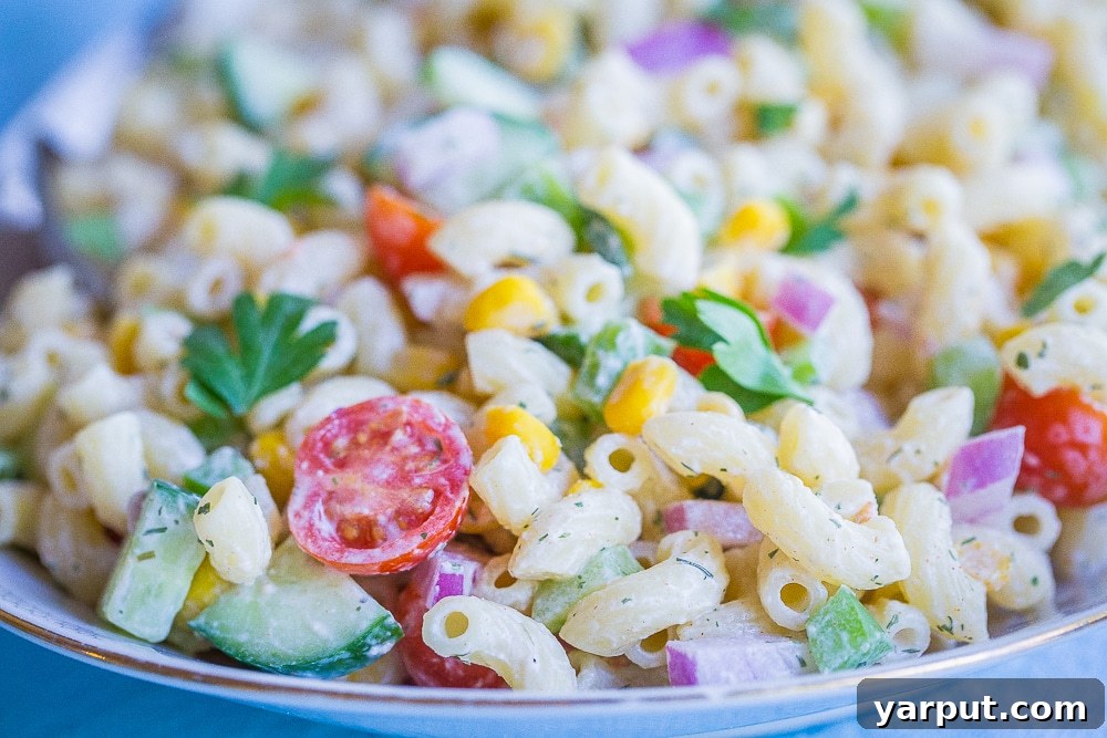Bright & Light Macaroni Salad Without Mayo 3 Close-up front view of the healthier mayo-free macaroni salad, highlighting the colorful pasta and vegetable mix on a serving dish with spoons.