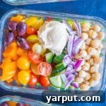 A top-down view of a fully assembled Greek Salad Meal Prep Bowl with toasted pita croutons.