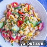 A top-down view of the Summer Vegetable Pasta Salad with Chickpeas, served in a white bowl.