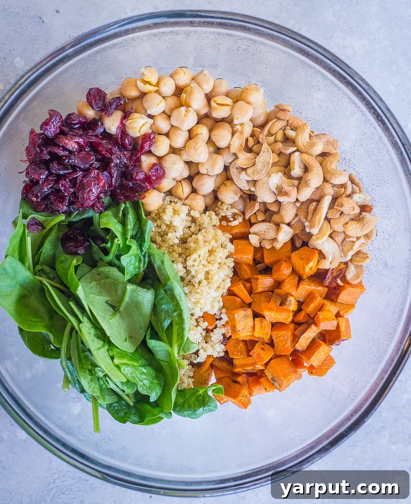 Golden Curry Quinoa Power Bowl 3 A vibrant bowl filled with individual ingredients for the Quinoa Chickpea Sweet Potato Salad, showcasing fresh spinach, diced sweet potatoes, and chickpeas.