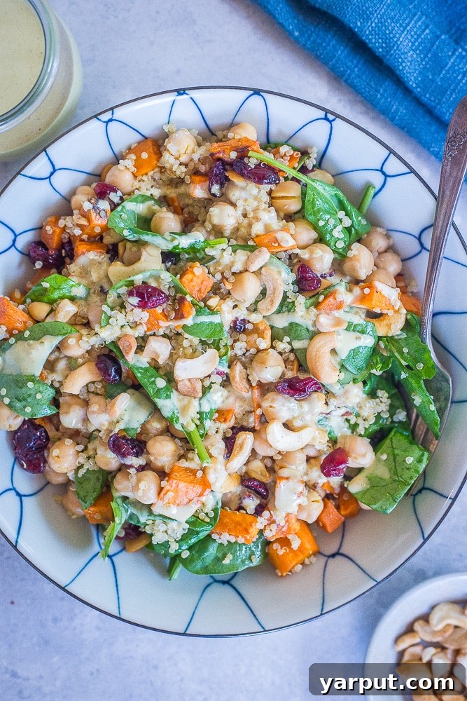 Golden Curry Quinoa Power Bowl 4 A large, inviting bowl of Quinoa Chickpea Sweet Potato Salad with a separate jar of the creamy Curry Tahini Dressing, beautifully arranged on a rustic table.