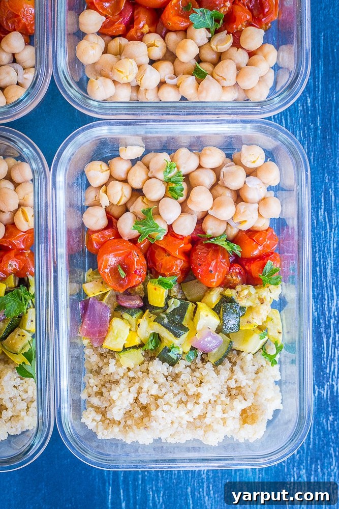 Roasted Summer Harvest Meal Prep Bowls 4 Three prepared Roasted Summer Vegetable Meal Prep Bowls, featuring roasted zucchini, summer squash, cherry tomatoes, quinoa, and chickpeas, arranged neatly on a blue surface, ready for a healthy week of lunches.