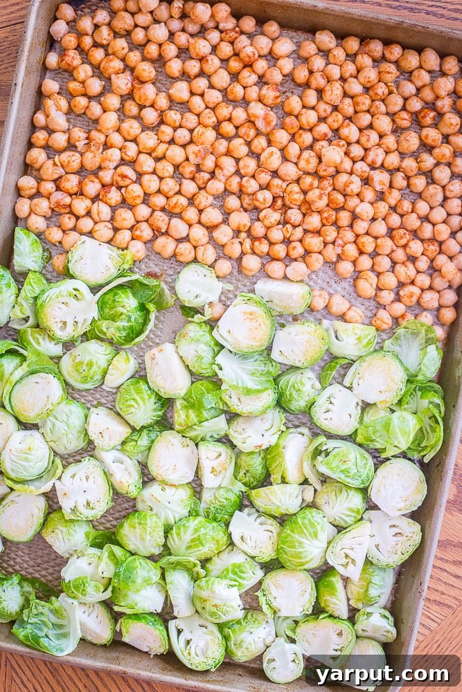 Golden Roasted Brussels & Chickpea Bowls 3 Brussels sprouts and chickpeas evenly spread on a sheet pan, drizzled with olive oil and seasoned, prior to roasting for the healthy meal prep bowls.