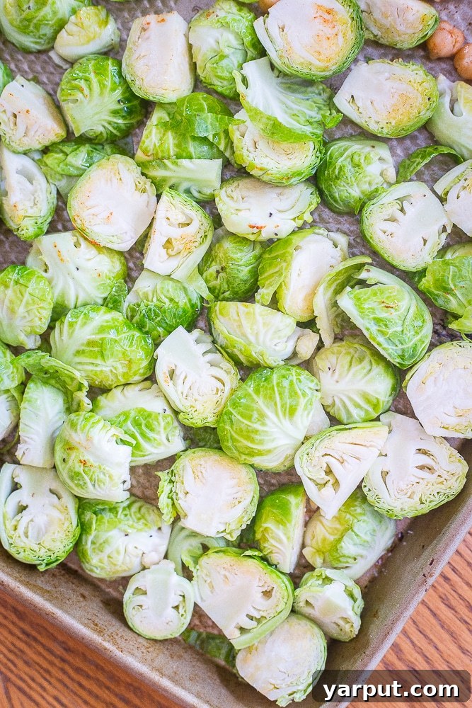 Simply Irresistible Roasted Brussels Sprouts 3 A tray of uncooked Brussels sprouts seasoned with olive oil, salt, and pepper, ready for roasting.