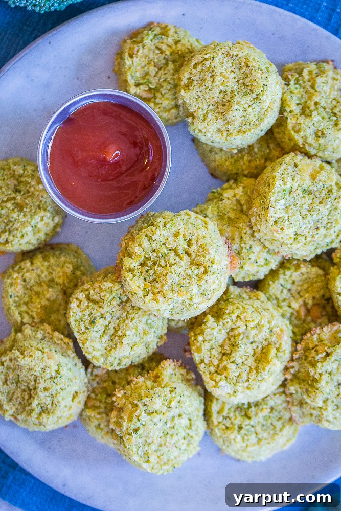 Broccoli Cheddar Power Poppers 5 A large, overflowing plate of golden-brown Protein-Packed Broccoli Cheese Bites, ready to be enjoyed, with a vibrant red ketchup dip beside them.