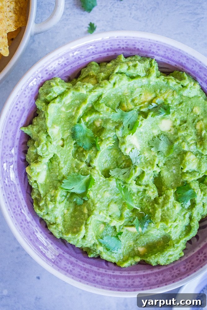 Perfect Guacamole Made Simple 5 A bowl of The Best Easy Guacamole Recipe with a side of crispy tortilla chips, inviting you to dig in.