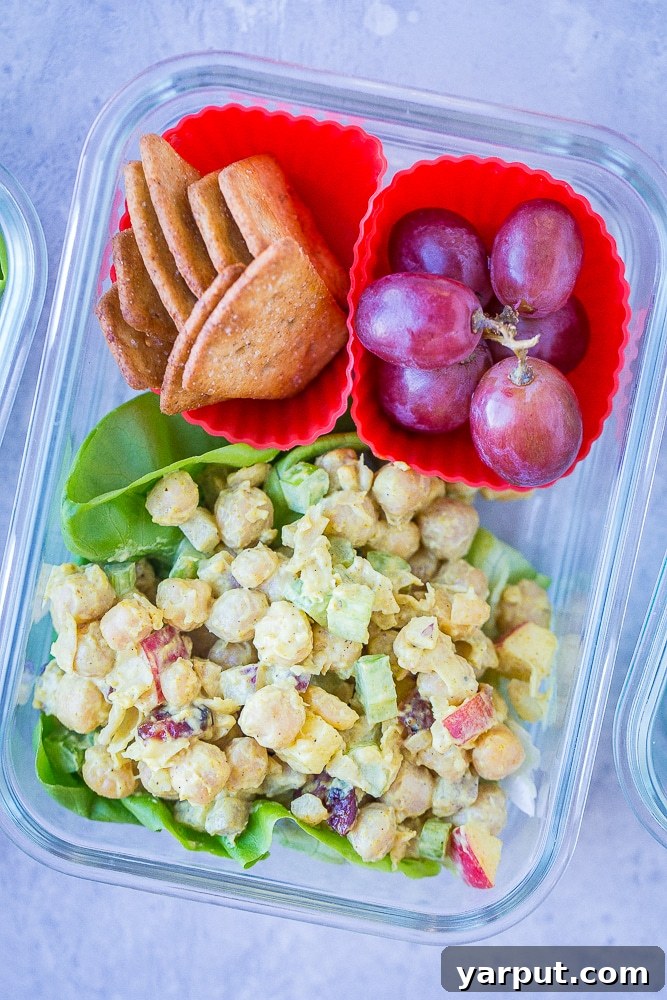 Vibrant Curried Chickpea Lunch Boxes 3 Close up of a single Curried Chickpea Salad Meal Prep Bowl, showcasing the texture of the chickpea salad, fresh lettuce, and side compartments for crackers and grapes