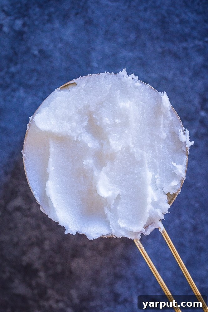 Measuring cup filled with solid, room temperature coconut oil