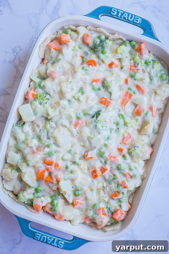Creamy Vegan Pot Pie in a baking dish before being baked, showing a rich vegetable filling without the top crust