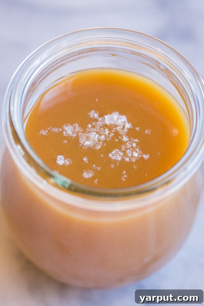 Silky Tahini Maple Vegan Caramel 5 close up of tahini caramel sauce in a jar with flaky sea salt sprinkled on top