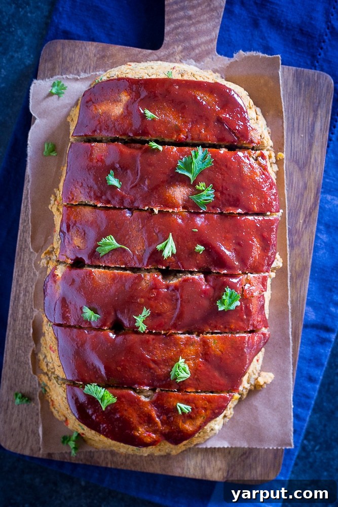 Hearty Lentil and Chickpea Vegan Meatloaf 3 Top view of Easy Vegan Meatloaf with Lentils and Chickpeas cut into slices on a cutting board, garnished with fresh herbs