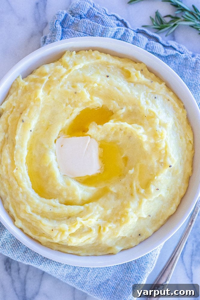 Velvety Vegan Mash 4 A close-up view of a bowl of creamy vegan mashed potatoes made with Yukon Gold potatoes, showcasing their rich yellow tint and smooth texture.