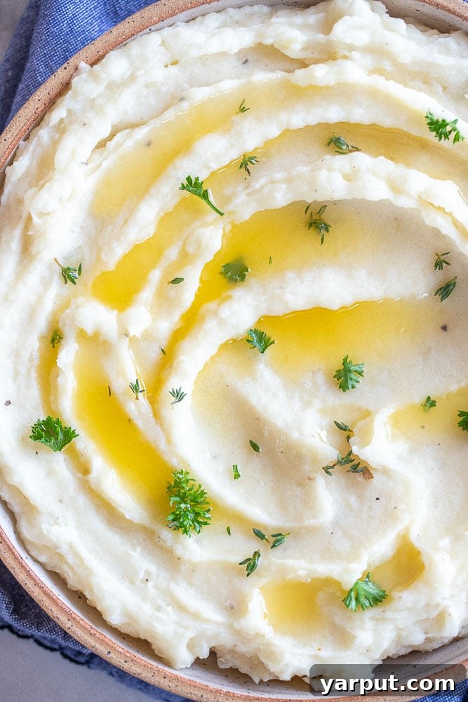 Velvety Vegan Mash 6 A beautiful close-up shot of a single serving of creamy mashed potatoes, garnished with a sprig of fresh rosemary and a pat of melted vegan butter.