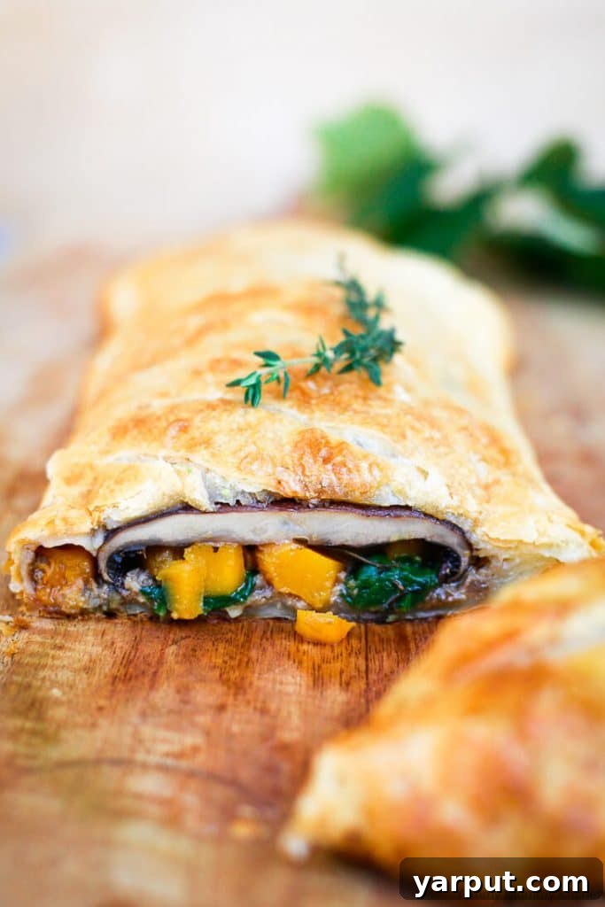 67 Vegan Holiday Recipes: Appetizers, Side Dishes, Salads, Main Courses, and Desserts 48 Vegetarian Mushroom Wellington sliced on a board