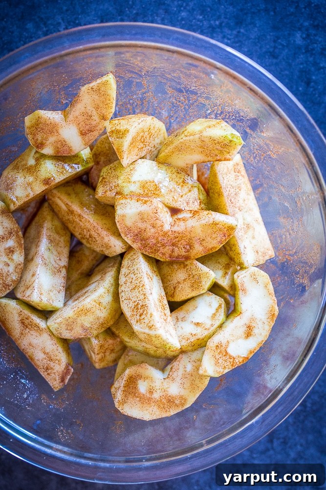 Simple Apple Pie Morsels 3 A bowl of freshly sliced apples, seasoned generously with cinnamon and sugar, prepared for Easy Apple Pie Bites.
