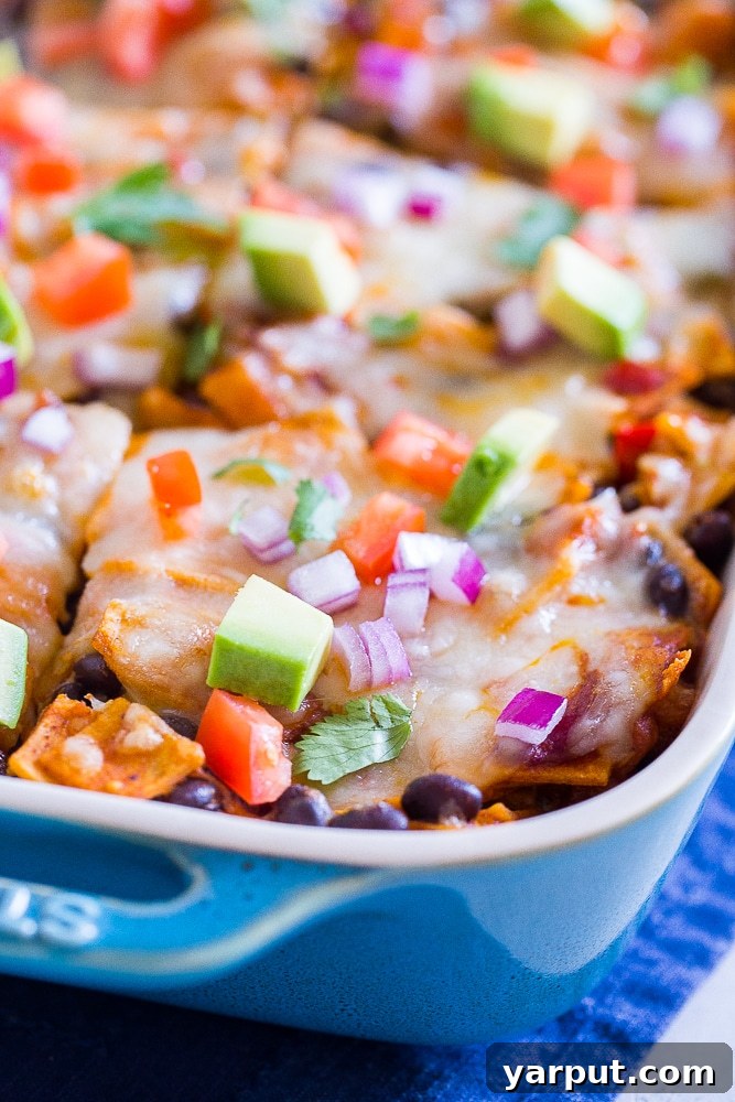Close up of a pan of Black Bean Enchilada Casserole with Butternut Squash, showing the gooey cheese and roasted vegetables