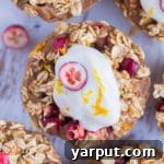 A vibrant Orange Cranberry Baked Oatmeal Cup with a dollop of yogurt on top.