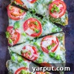 A close-up of a French Bread Pizza with pesto, broccoli, and tomato.