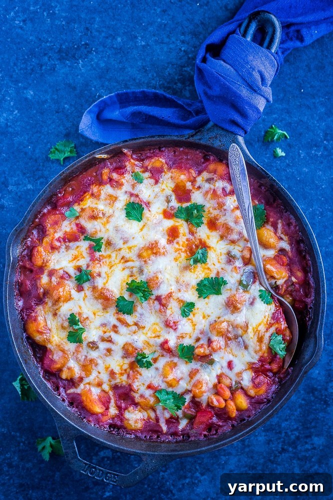 One-Pan Gnocchi Pizza Bake: 30-Minute White Bean Delight 4 A large pan filled with the finished 30-Minute Gnocchi Pizza Bake with White Beans, garnished with fresh herbs and a serving spoon.