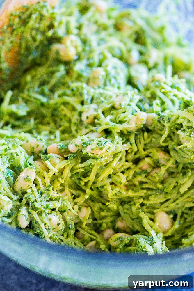 Spaghetti Squash Gratin with Pesto and White Beans 3 A bowl of freshly cooked spaghetti squash mixed with bright green pesto and creamy white beans, ready for assembly into melts.