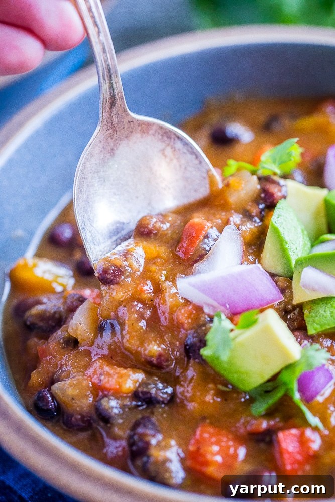 A spoon scooping into the rich, thick texture of Butternut Squash Chili with Black Beans.
