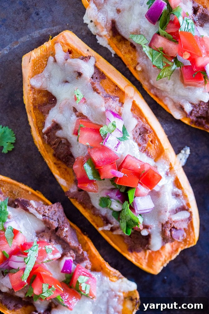 Close-up view of two Sweet Potato Tostadas loaded with refried beans and melted cheese, fresh from the oven
