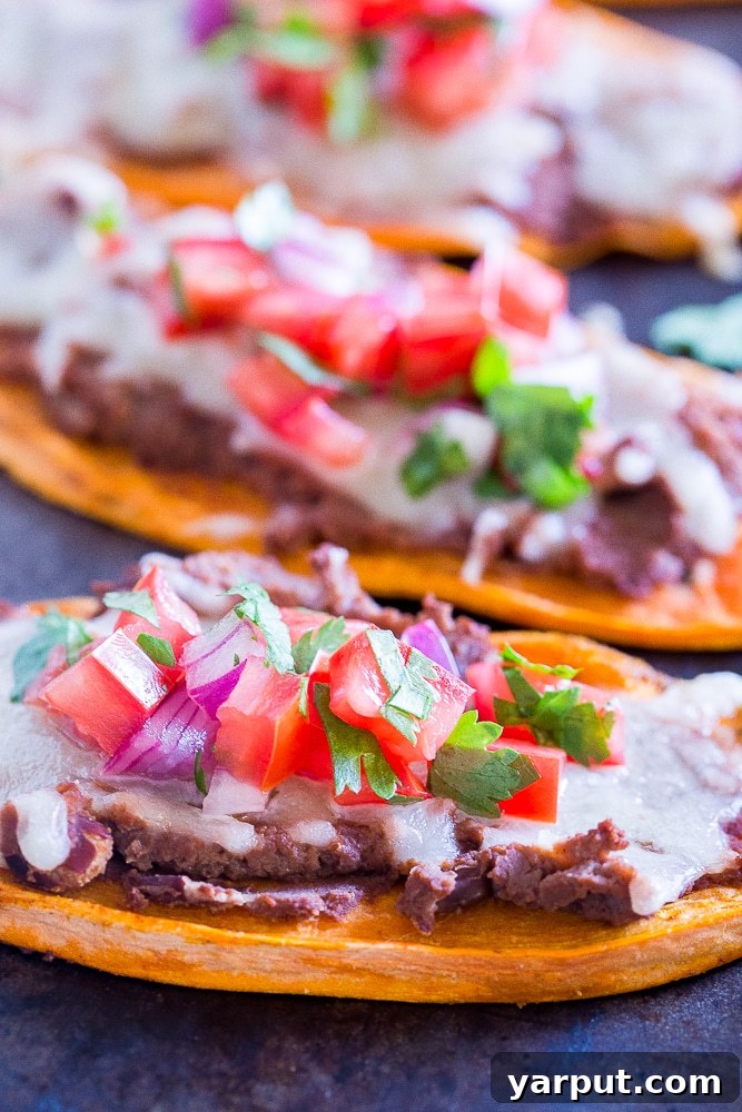 Another close-up shot of Sweet Potato Tostadas arranged neatly on a baking sheet, garnished with fresh herbs