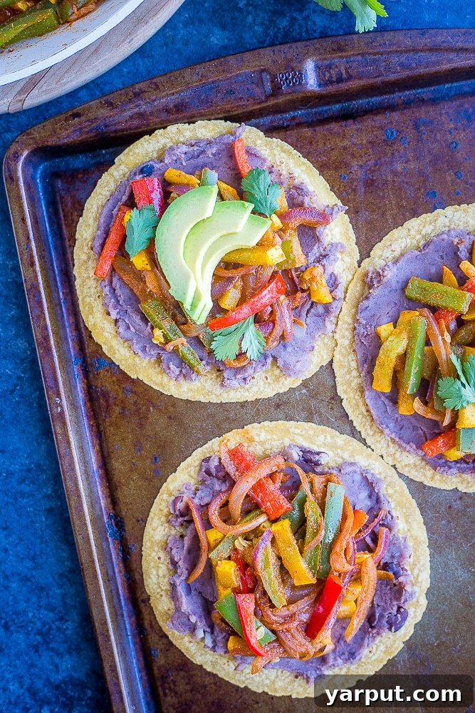 Sizzling 30-Minute Fajita Tostadas 5 A close-up shot of two perfectly cooked Fajita Tostadas on a sheet pan, garnished with fresh cilantro and avocado
