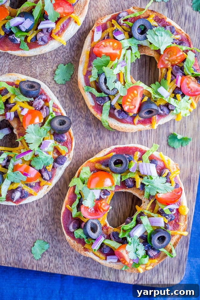 Fiesta Pizza Bagels 6 Five finished Taco Pizza Bagels artfully arranged on a wooden cutting board, showcasing their vibrant toppings.