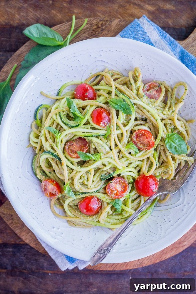 20 Minute Creamy Avocado Pesto Zucchini Noodles 2 A vibrant bowl of Avocado Pesto Zucchini Noodles, garnished with cherry tomatoes and fresh herbs, ready to be enjoyed.