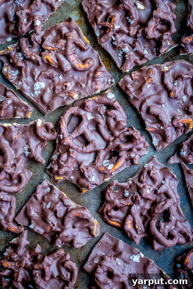 Overhead flatlay view of a baking sheet covered with various pieces of finished Chocolate Pretzel Bark, highlighting its rustic appeal and enticing texture.
