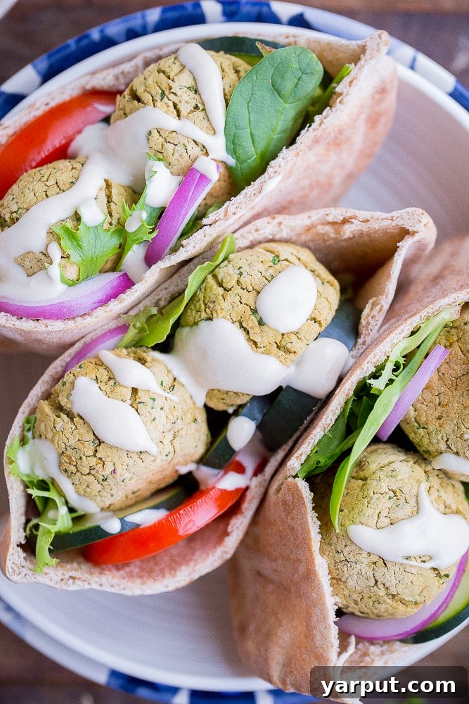 Foolproof Homemade Falafel 7 Close-up shot of a perfectly assembled Easy Homemade Falafel pita sandwich, generously filled with fresh vegetables and drizzled with sauce, ready for a delicious bite.