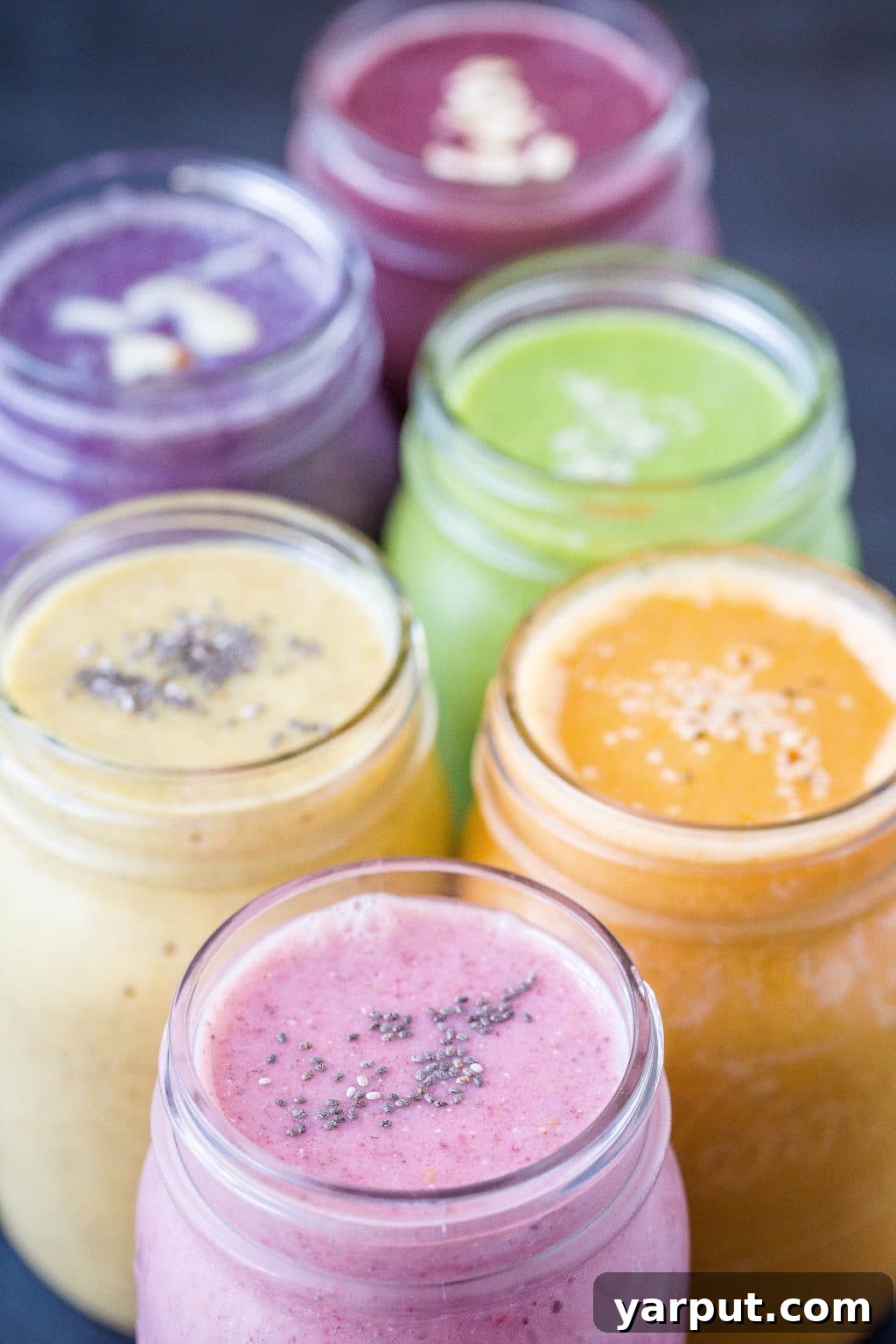 Six healthy smoothie recipes in clear glass jars