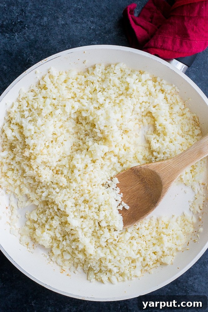 Crafting Delicious Cauliflower Rice 2 Pan of freshly cooked cauliflower rice with a wooden spoon, ready to serve as a healthy low-carb side dish